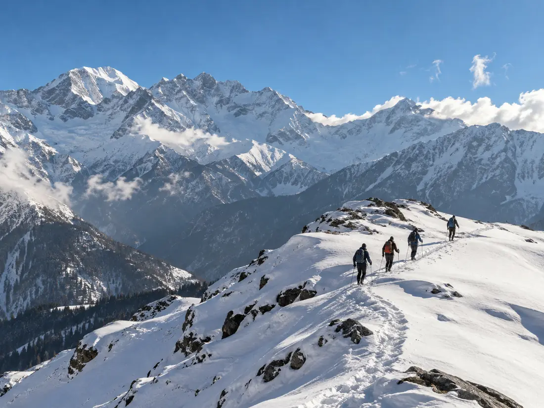 A line of trekkers walking along a snowy ridge under big Himalayan peaks